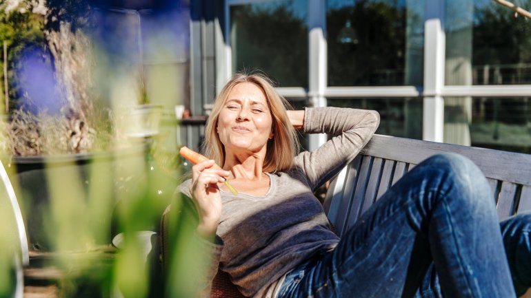 Frau in den Wechseljahren genießt Karotte in der Sonne.