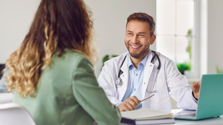 Arzt erklärt seiner Patientin freundlich etwas im Sprechzimmer