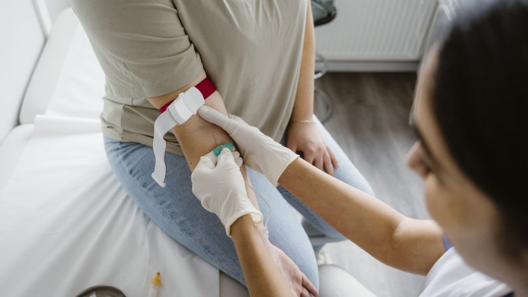 Medizinische Fachangestellte nimmt bei einer Frau Blut aus dem rechten Arm ab